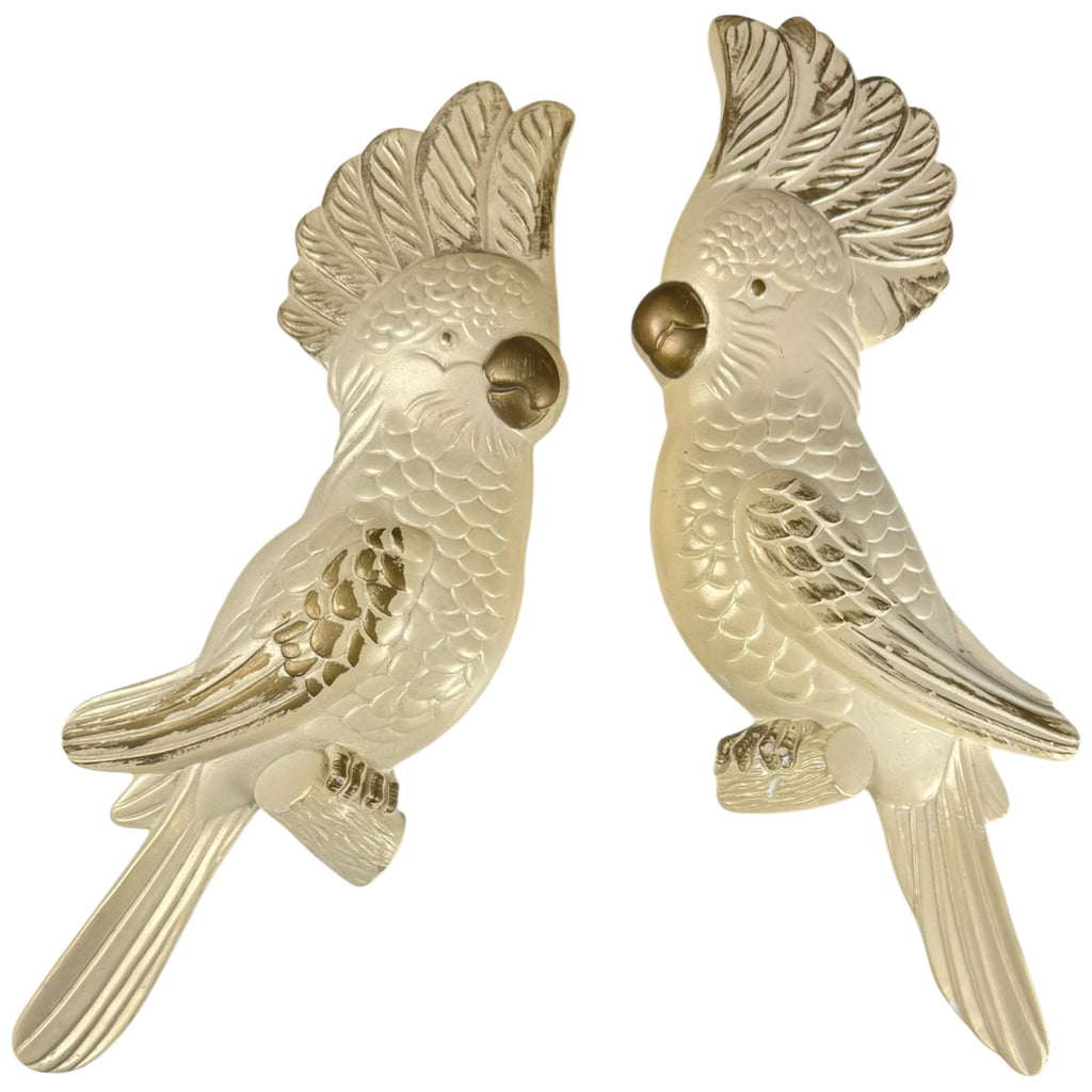 Pair of vintage 1973 Miller Studio chalkware cockatoo wall plaques in cream and antique gold, facing one another.