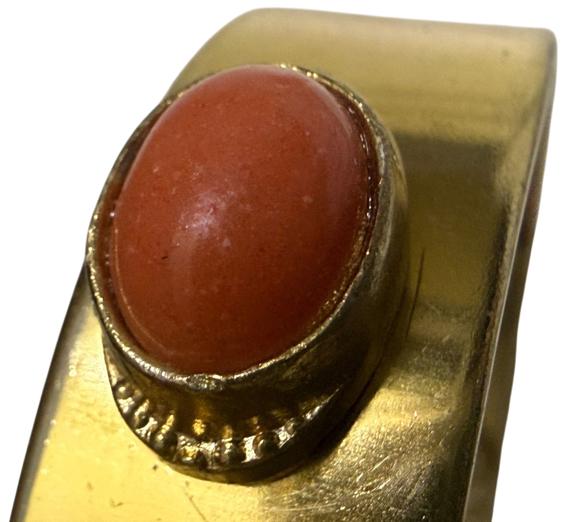 A close-up of a vintage gold toned bracelet featuring a large, oval cabochon  stone in a textured gold toned bezel setting