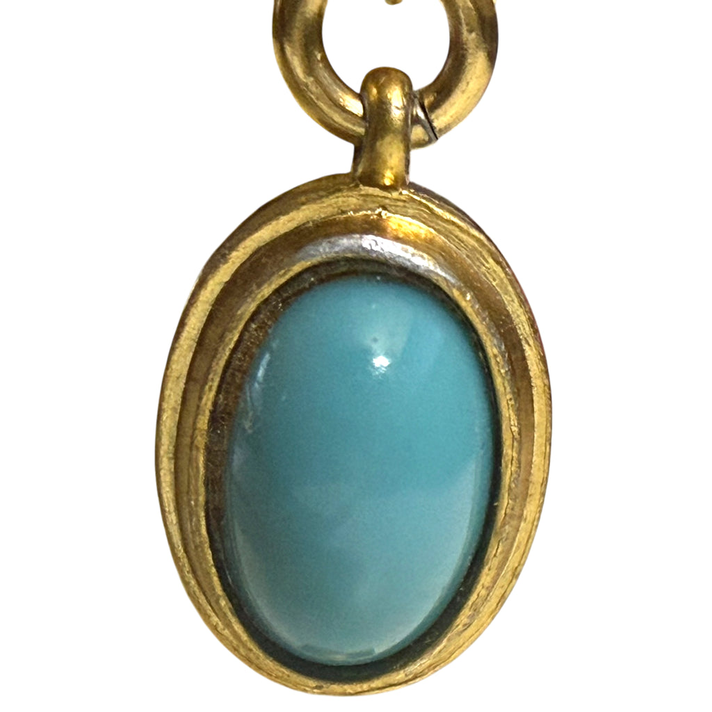 turquoise coloured cabochon dangling from a cuff bracelet