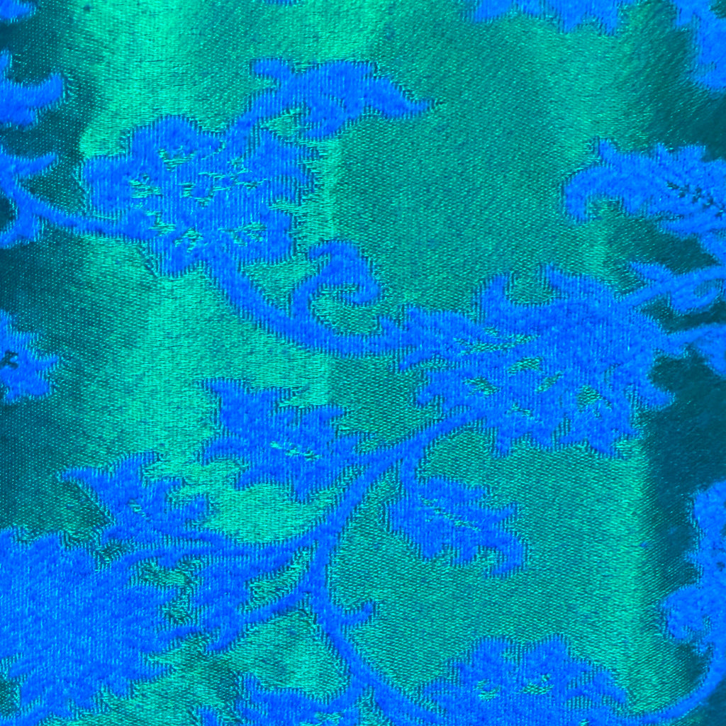 Close-up of emerald-green and cobalt-blue woven floral brocade fabric with satin finish on vintage Rappi dress