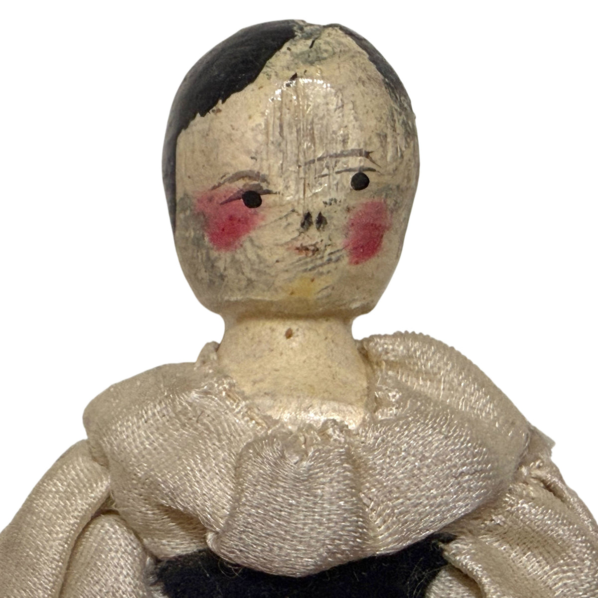 Close-up of Grödnertal doll's hand-painted wooden face with black hair, rosy cheeks and cream silk blouse collar.