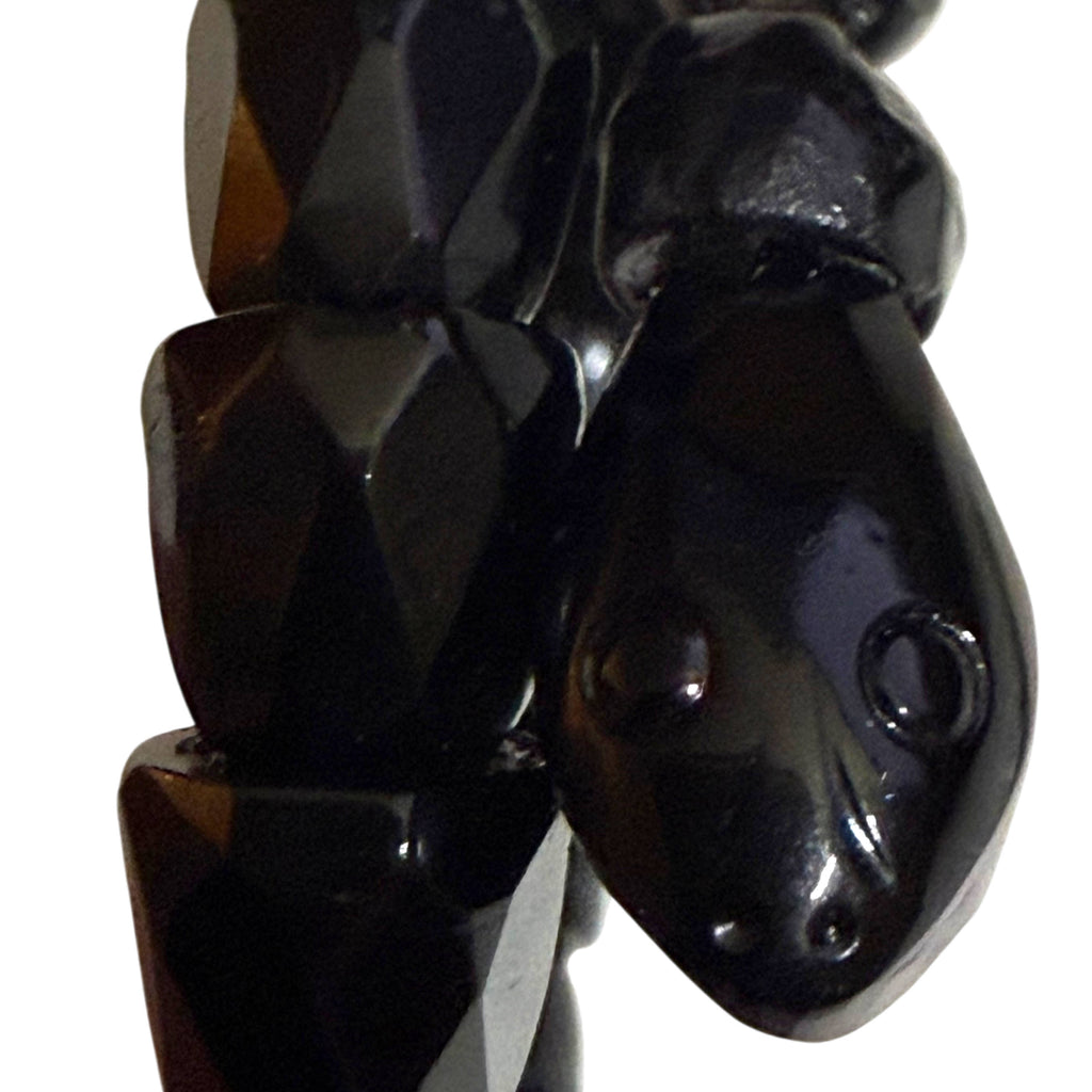 Extreme close-up of antique black jet-style snake bracelet head showing carved eye, nostril and mouth