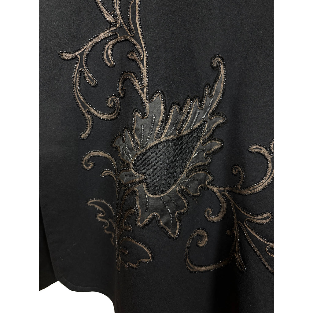 Detail of thistle-like floral appliqué and golden-brown corded embroidery on black wool