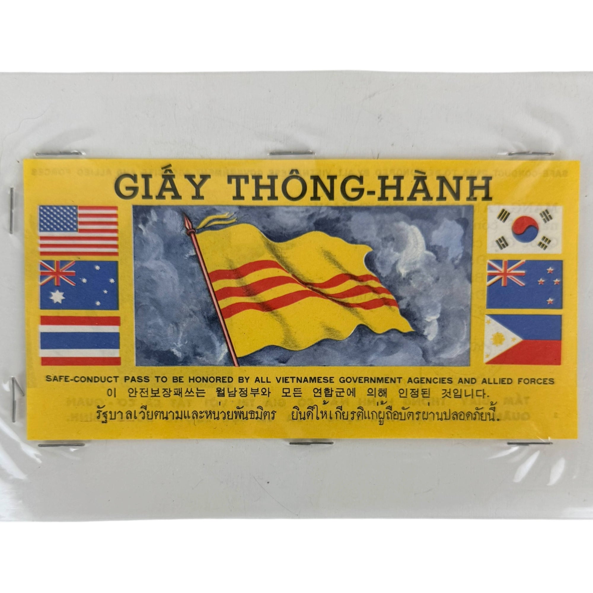A vintage yellow Vietnamese safe-conduct pass sealed in clear plastic packaging, featuring the French Indochina flag in the center and flags of the United States, Australia, South Korea, and the Philippines on the sides.