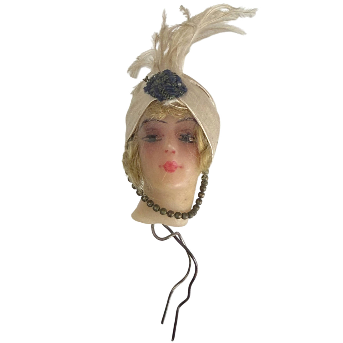 Antique wax doll head with original metal mounting wire extending beneath the neck and elaborate feathered turban