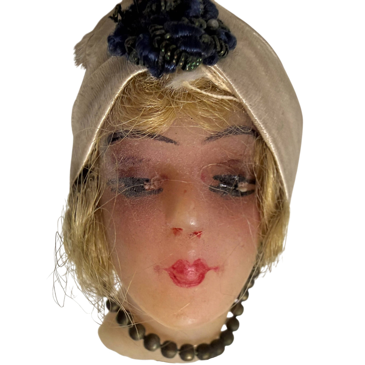 Close-up of antique wax doll head with dark blue embroidered turban ornament, painted eyes and red lips