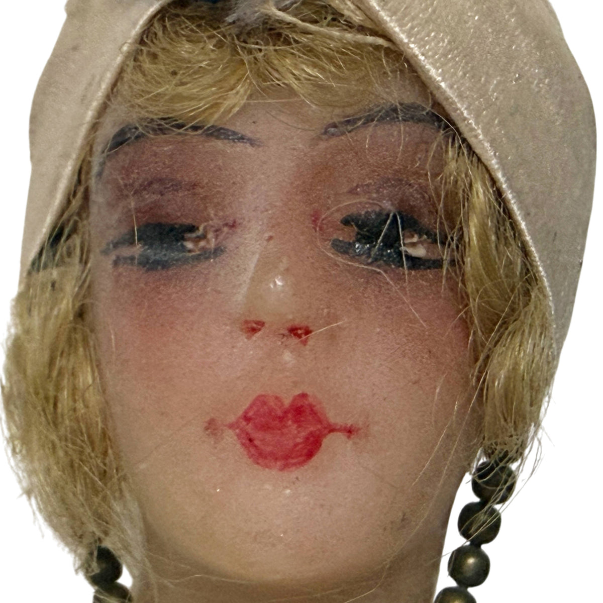 Detailed close-up of antique wax doll face showing hand-painted eyebrows, heavily lidded eyes, rosy cheeks and red lips