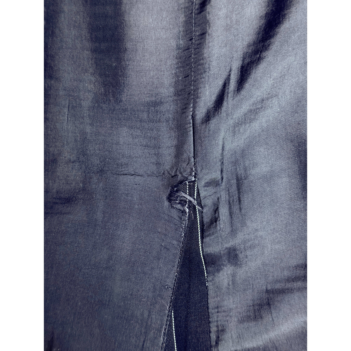 Close-up of minor fraying to skirt lining at top of kick vent, showing vintage condition detail