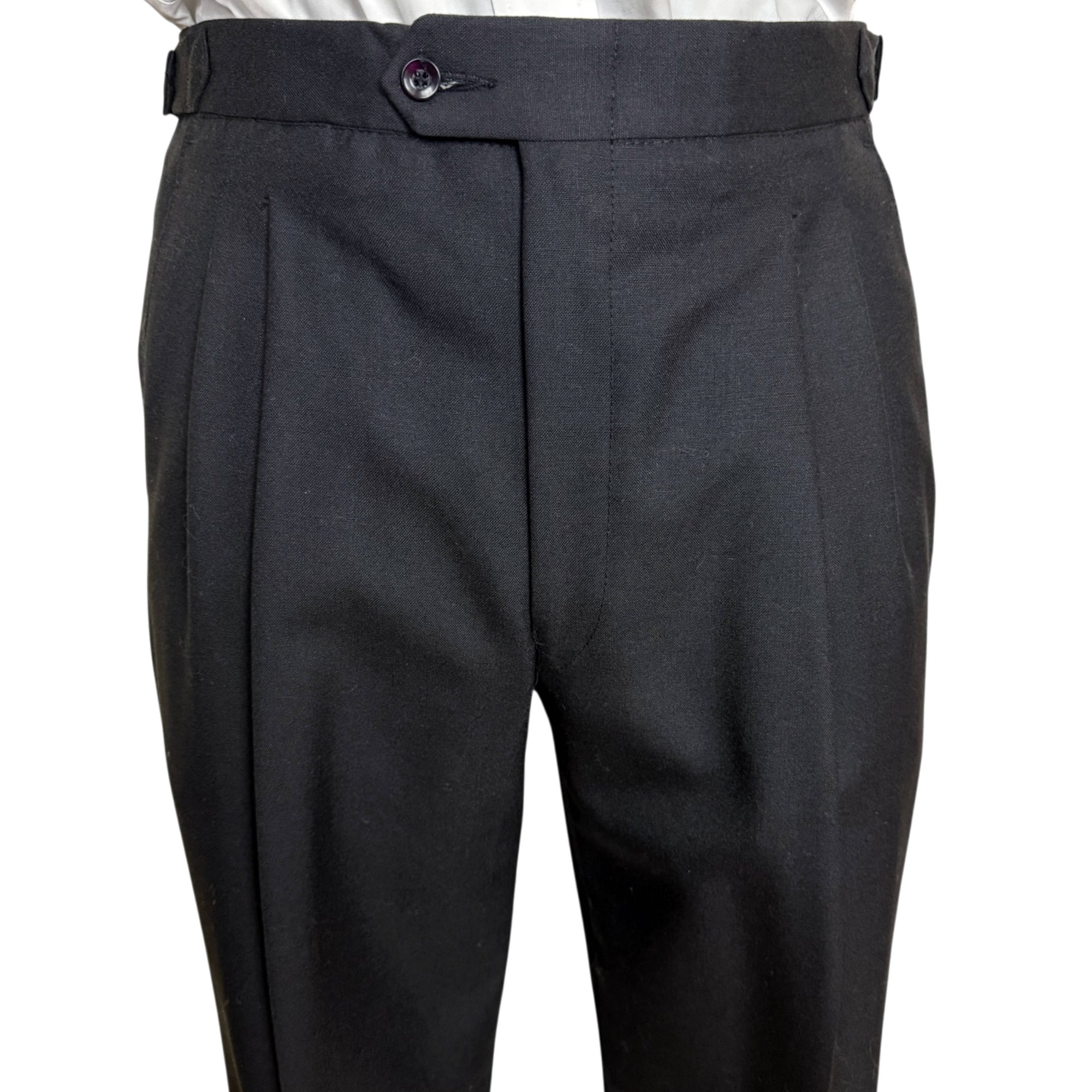 Close-up of black tailored trousers with front pleats and a button closure at the waistband, shown on a white background.